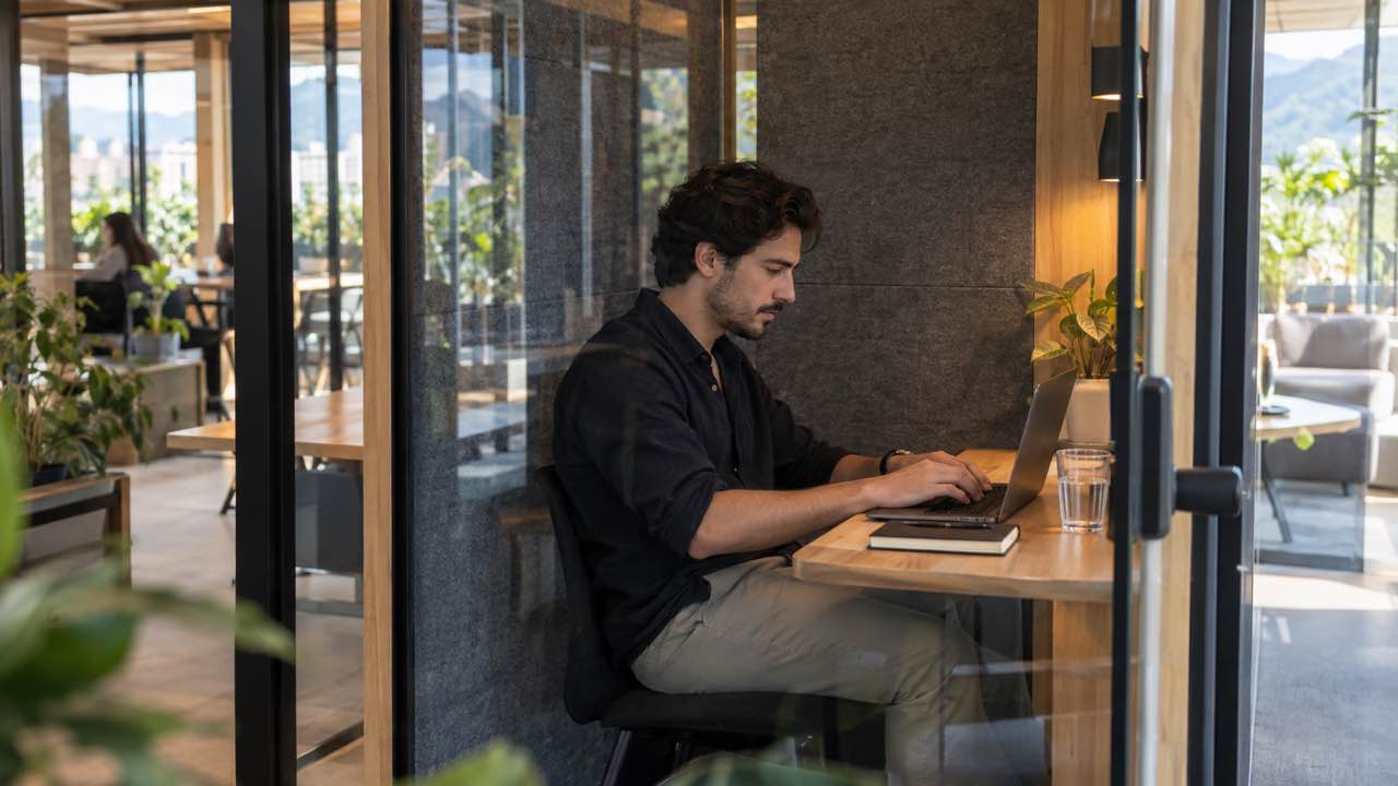 Profesional trabaja con computador en una cabina insonorizada